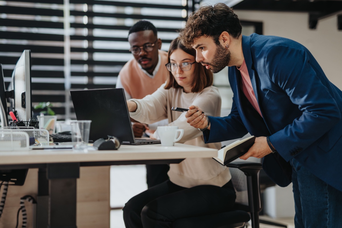 A photo of an office workers discussing in front of the laptop.