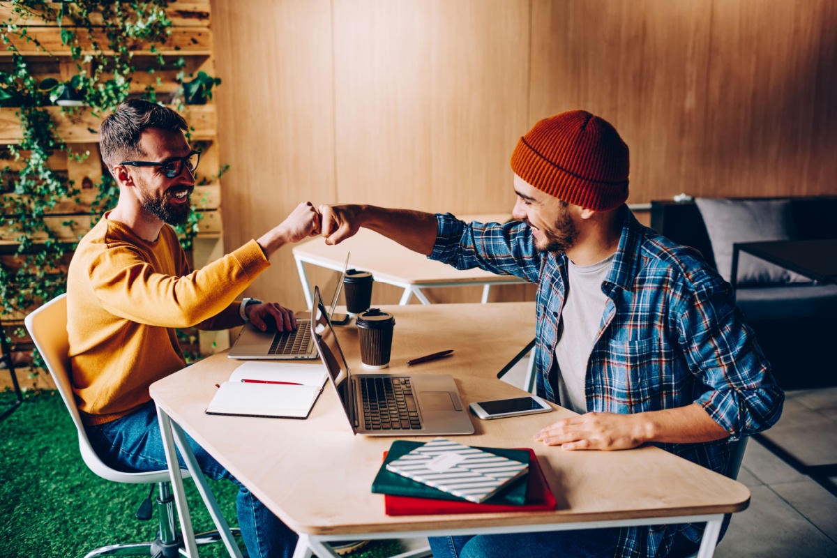 Two colleagues celebrating success with a fist bump in a modern coworking office.